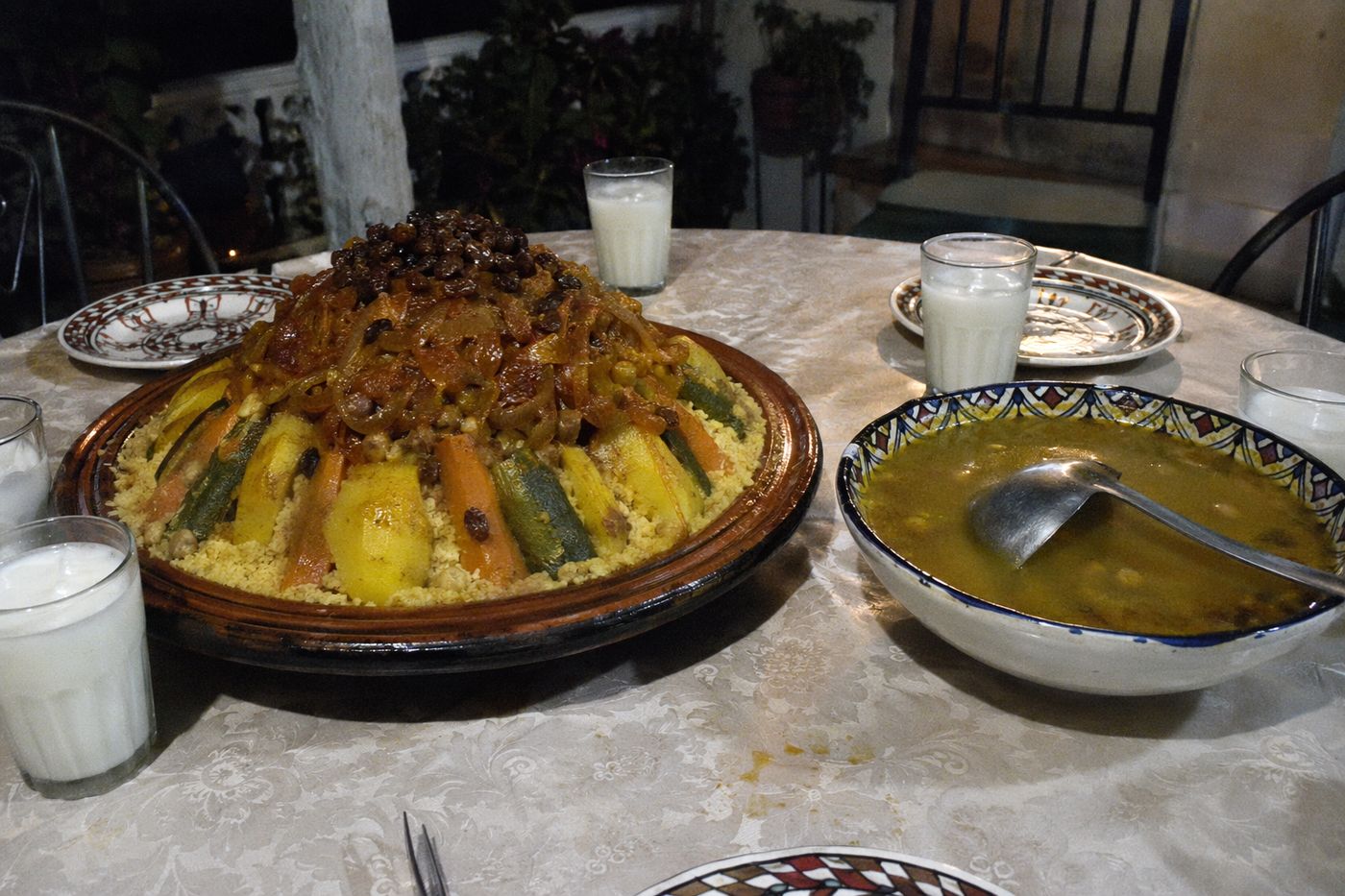 Couscous couronné de tfaya aux oignons confits et raisins, bol de bouillon et verres de lben à côté.
