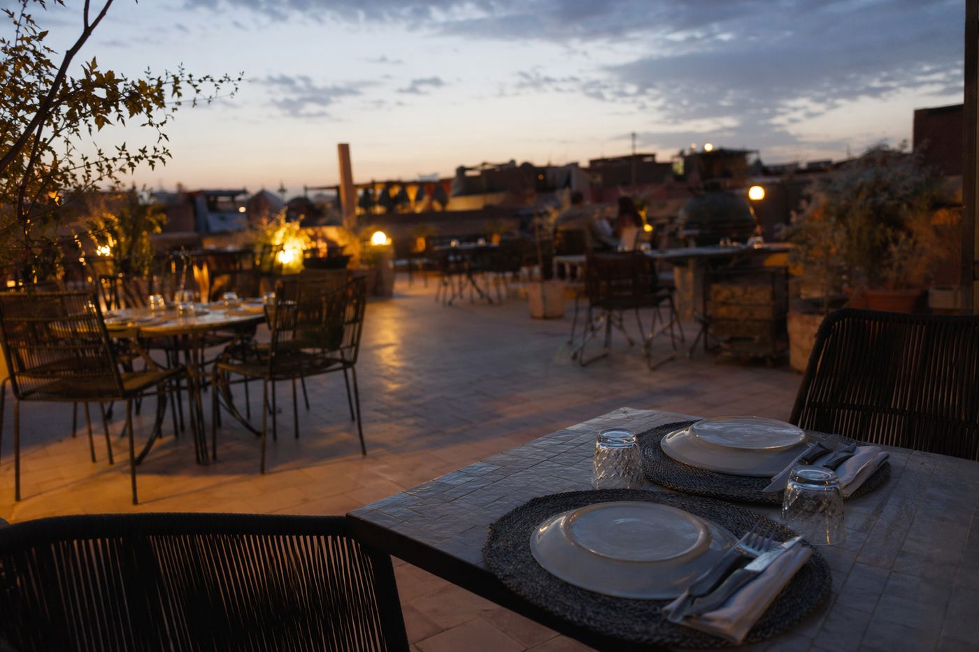 Terrasse de restaurant presque vide en tout début de service, dernière lueur du jour et premières ampoules allumées