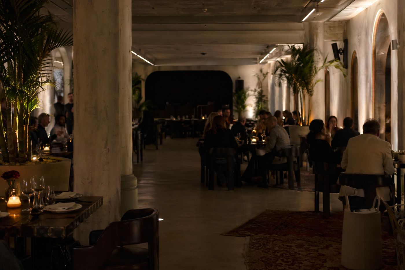 Salle de dîner-club calme à 20 heures, tables occupées au loin et cabine de DJ encore éteinte au fond