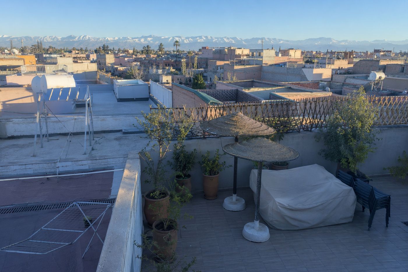 Petite terrasse de toit vue d'en haut au matin clair, chaises empilées et Atlas net à l'horizon.