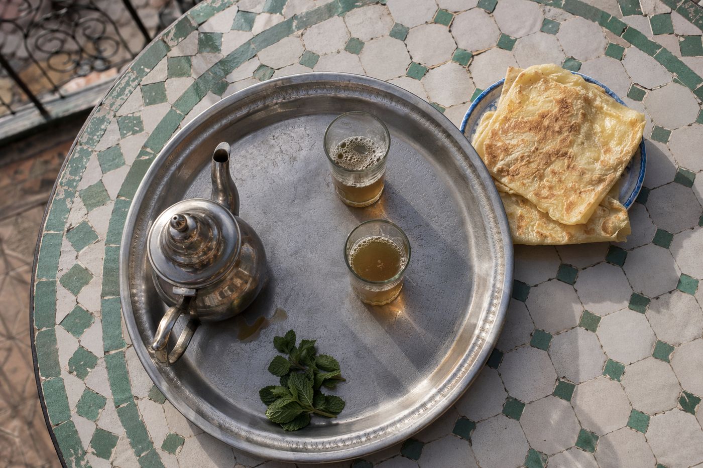 Plateau de thé à la menthe et msemen sur une table de terrasse de la médina au petit matin