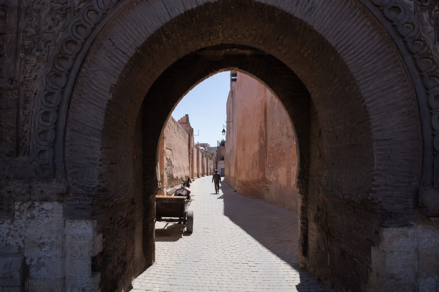 Rue de la Kasbah vue à travers l'arche de pierre sculptée de Bab Agnaou en plein midi