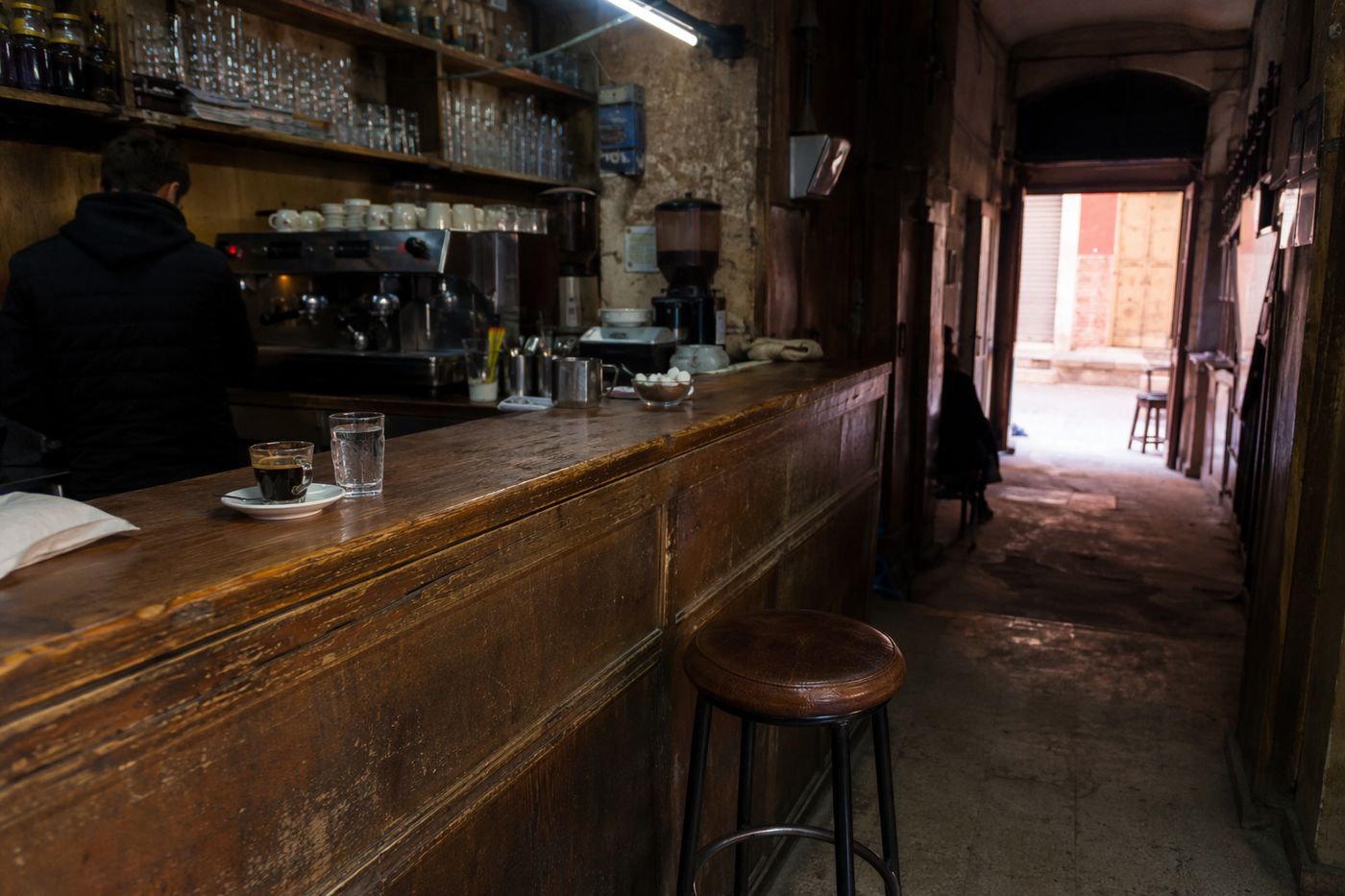 Comptoir en bois d'un café de la médina avec un seul tabouret, espresso servi au bord du zinc