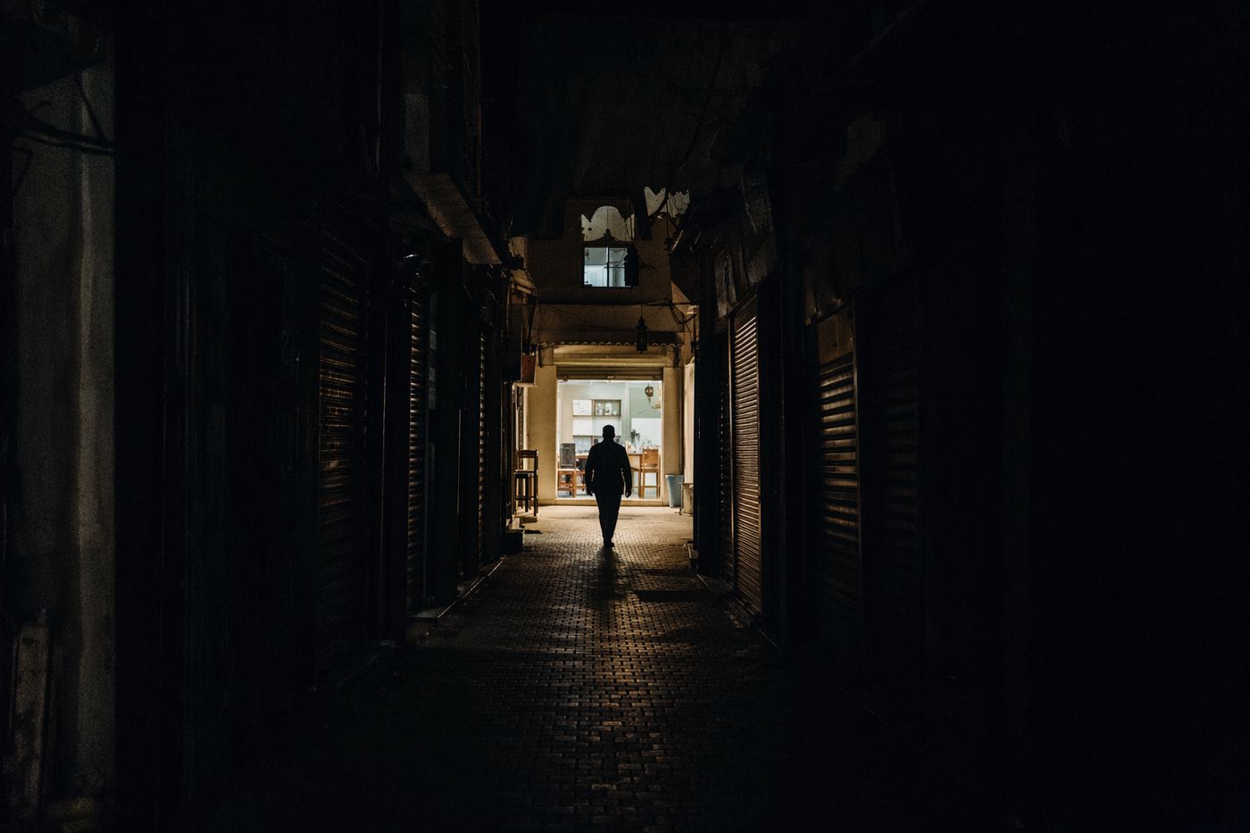 Ruelle sombre de la médina la nuit, une seule porte de restaurant éclairée au fond