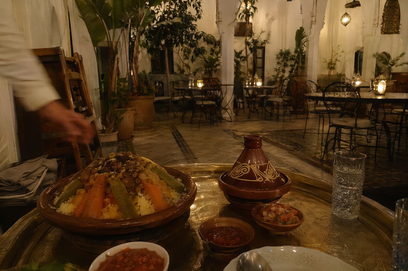 Couscous et tajine servis tard dans un patio de riad éclairé aux lanternes, salle presque vide