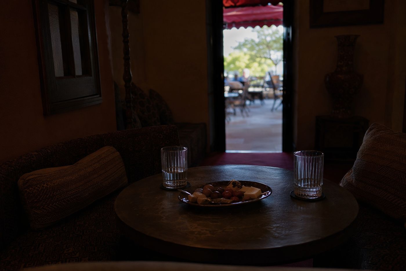 Table pour deux dans un salon calme à l'étage, patio lumineux visible par la porte ouverte