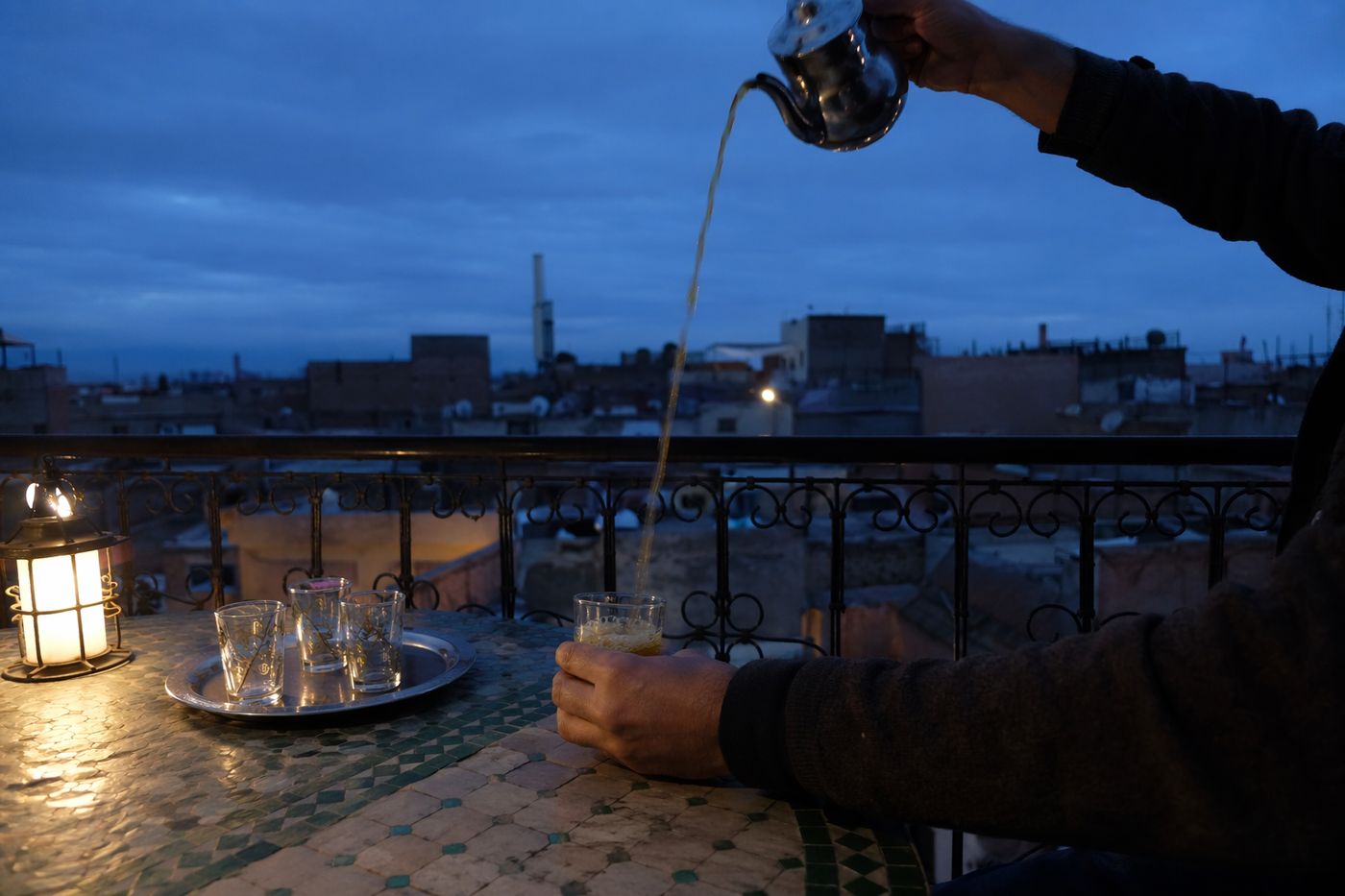 Mains versant du thé à la menthe sur une terrasse de toit de la médina à l'heure bleue