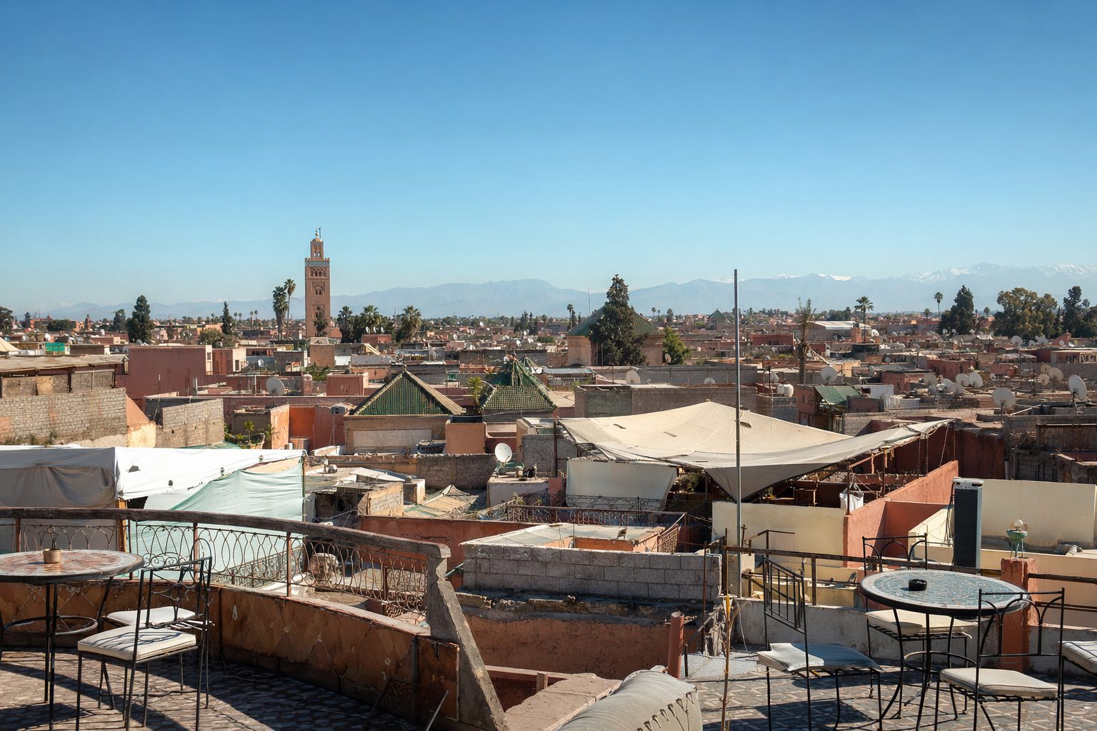 Panorama des toits de la médina de Marrakech à midi, terrasses et minaret de la Koutoubia au loin