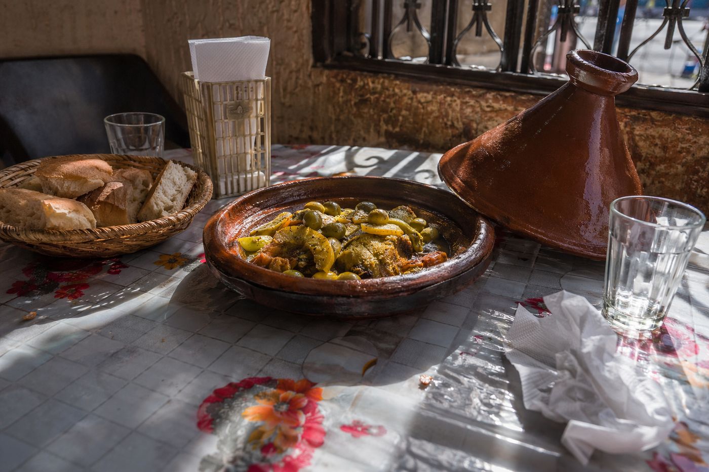 Tajine de poulet aux citrons confits ouvert sur la table simple d'un restaurant de quartier.