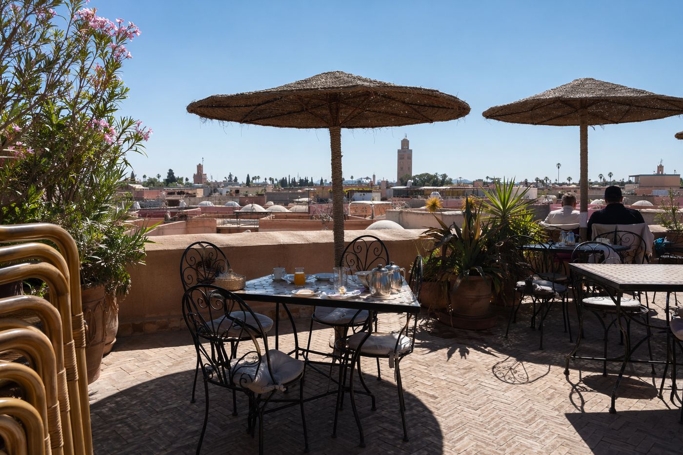 Terrasse de rooftop à Marrakech en matinée, tables sous parasols et toits de la médina en arrière-plan.
