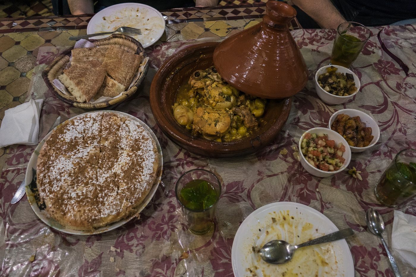 Vue de dessus d'un dîner marocain : pastilla, tajine au citron confit, pain, salades et thé à la menthe
