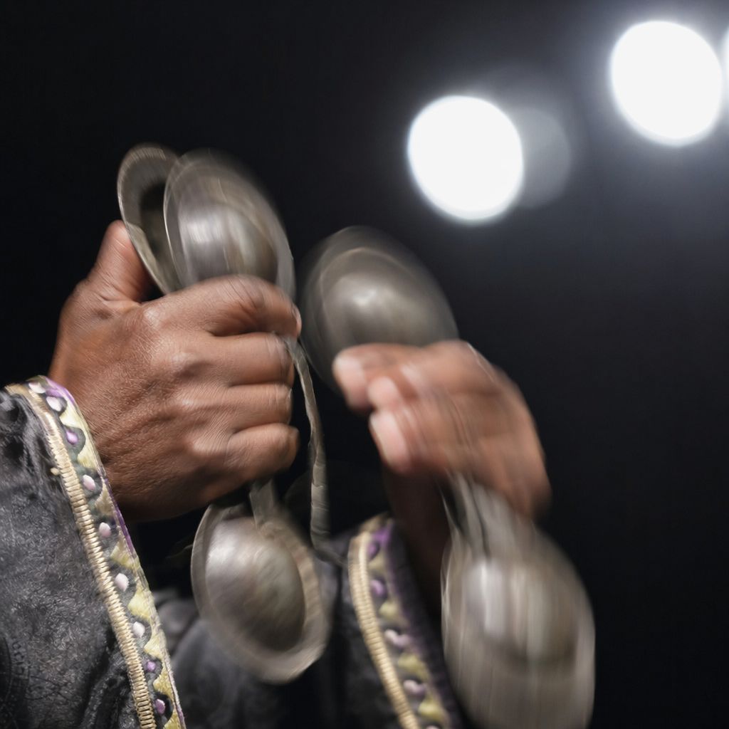 Gros plan sur des krakebs en métal entre les mains d'un musicien gnaoua, en plein mouvement