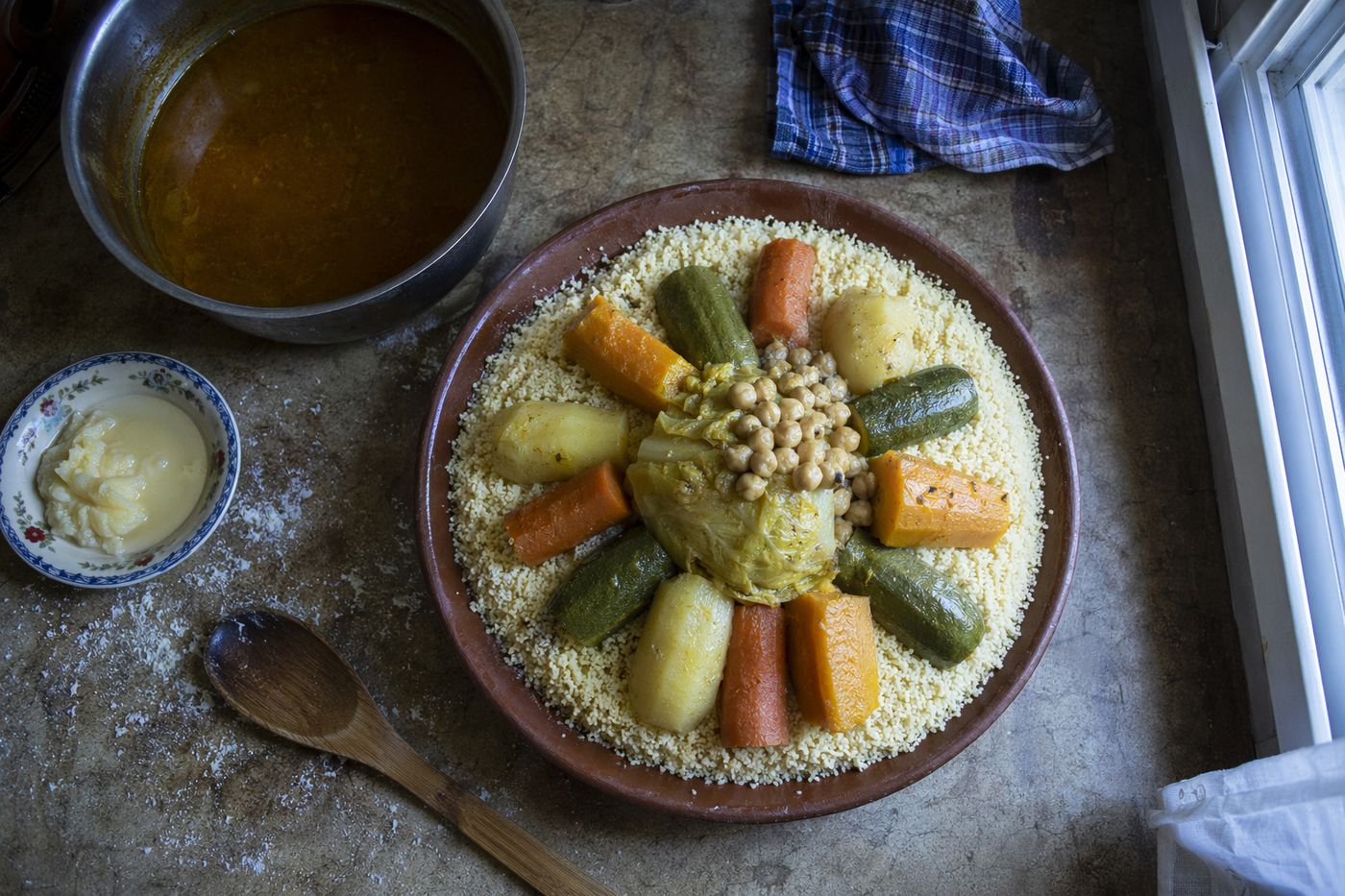 Plat de couscous aux légumes en préparation sur une table de cuisine, lumière du matin