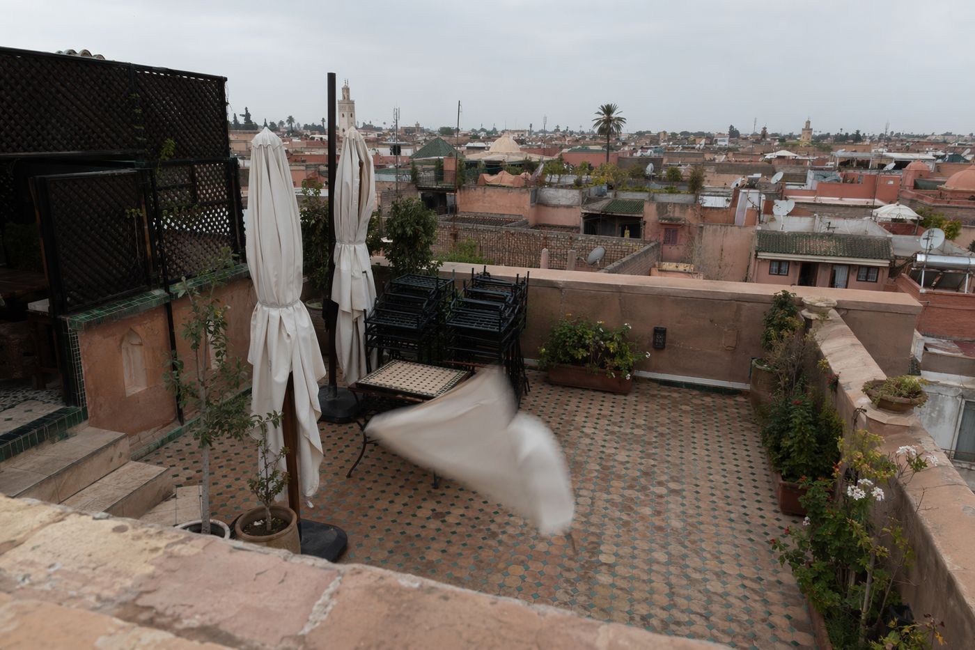 Terrasse de toit vide un jour d'hiver couvert, chaises empilées et parasols fermés.