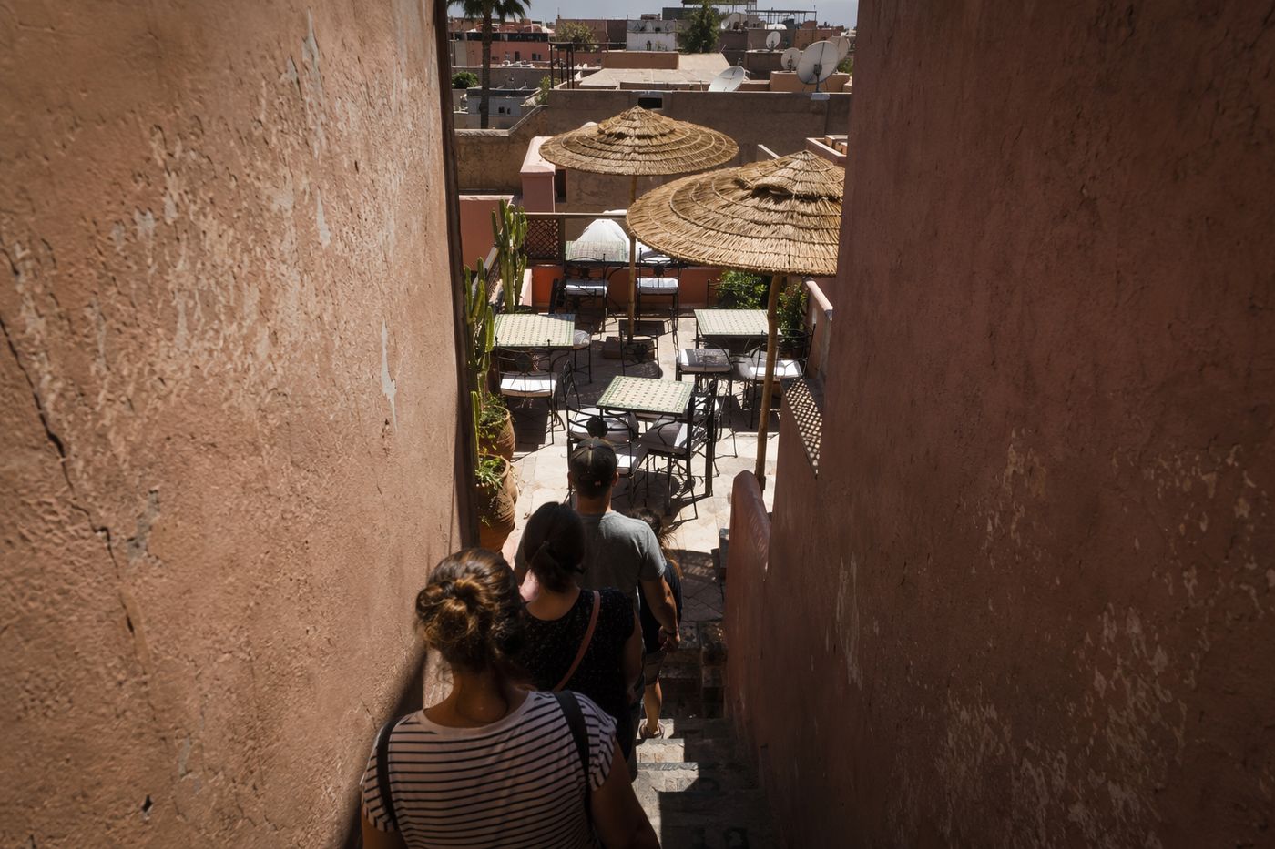 Petite terrasse de toit bondée sous le soleil de midi, file d'attente dans l'escalier.