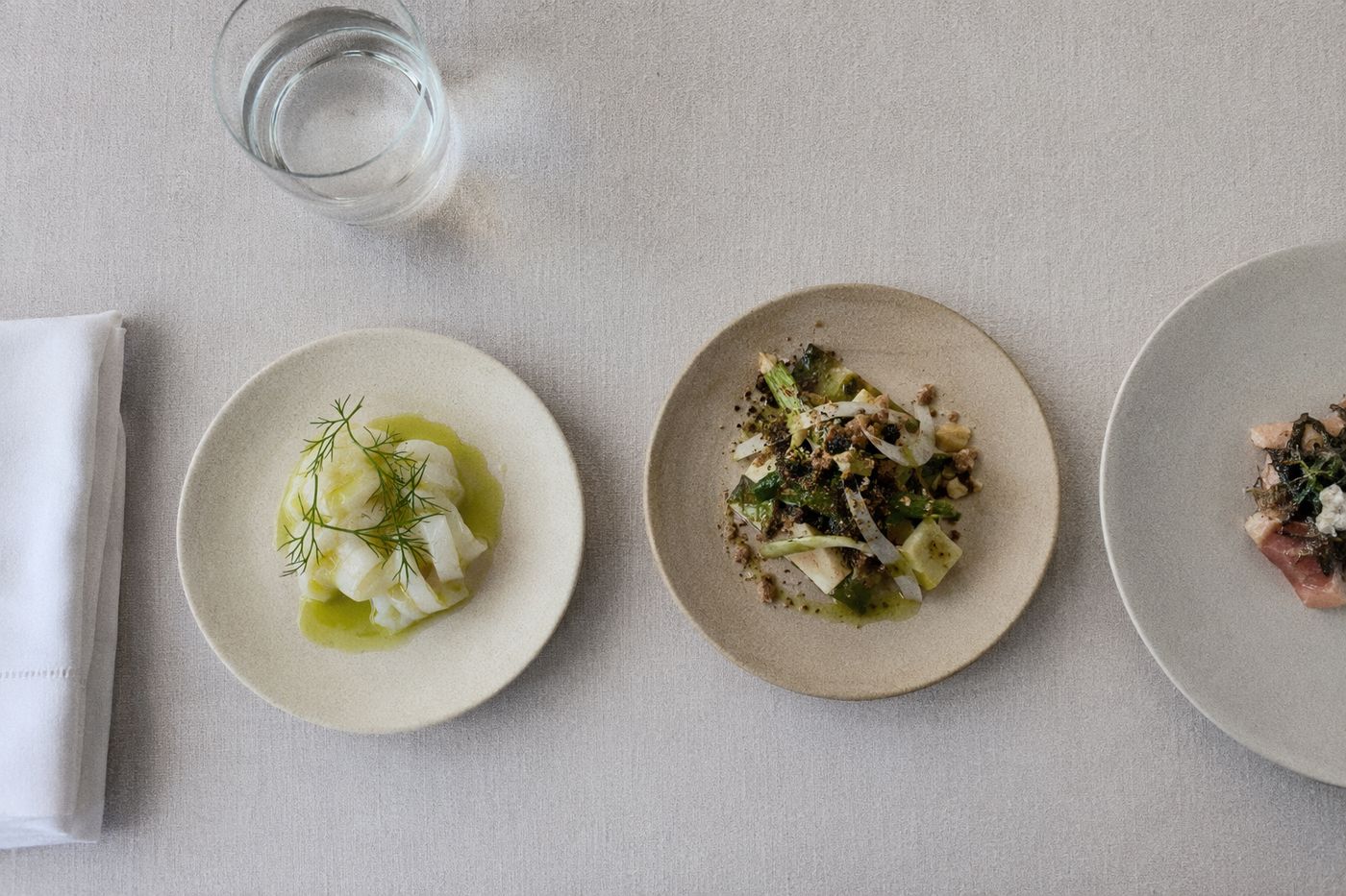 Vue du dessus de trois petites assiettes d'un menu déjeuner court alignées sur une table sobre.
